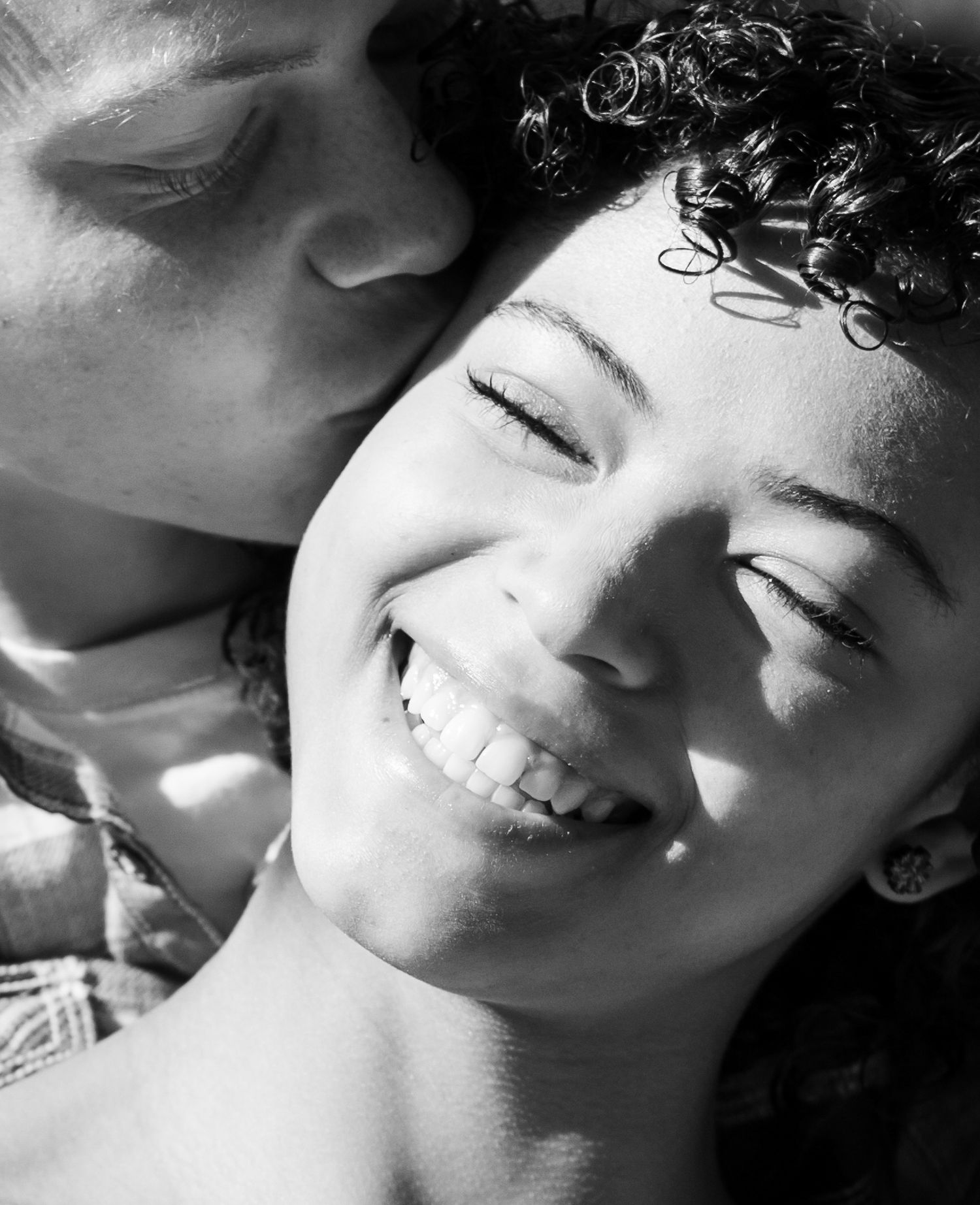 A close-up black and white portrait capturing a joyful intimate moment between a couple.