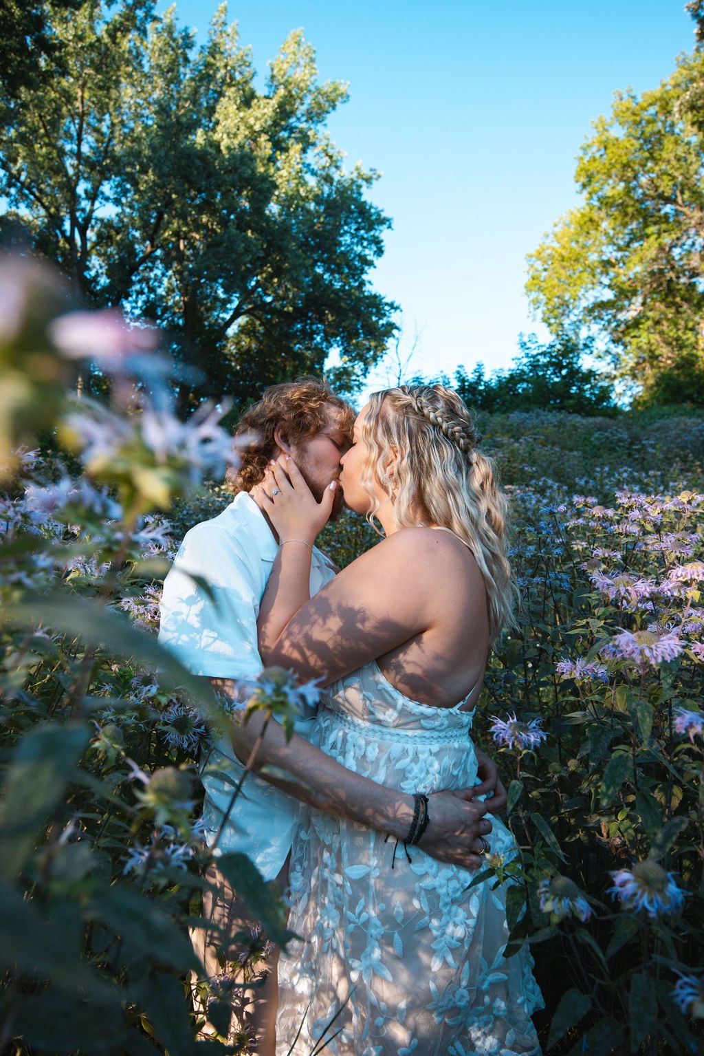 Intimate portrait of a couple embracing in a blooming flower garden on a sunny afternoon.