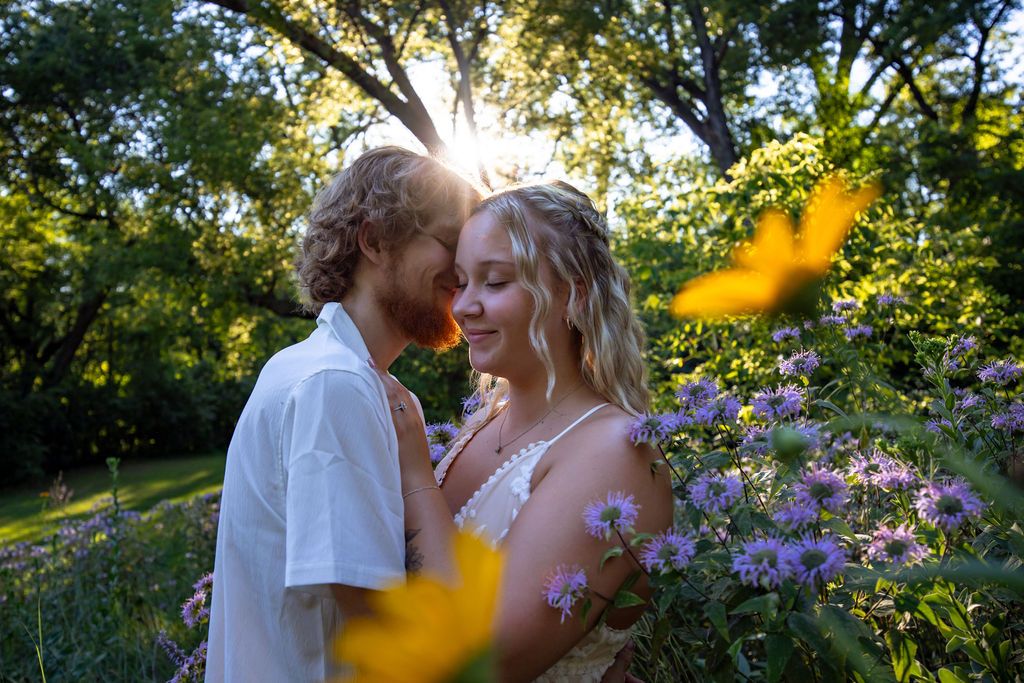 Golden hour garden portrait with purple wildflowers and sunlight streaming through trees.