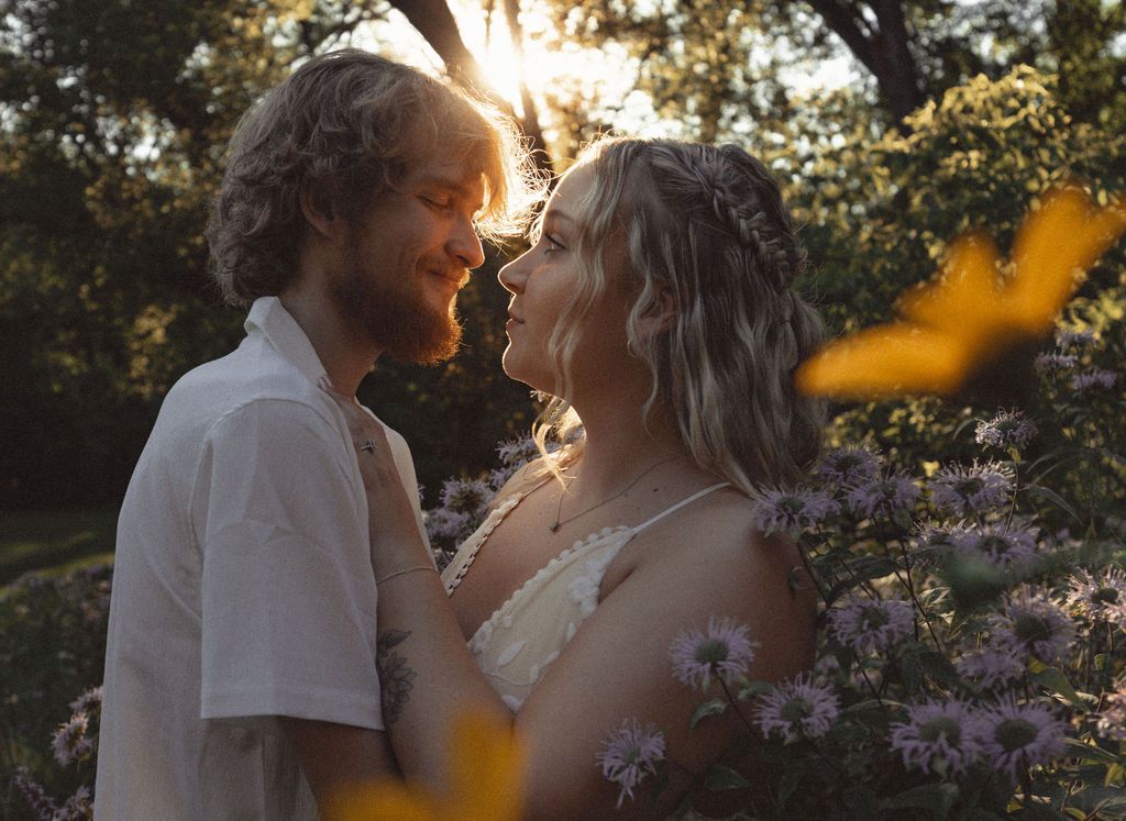 Romantic sunset portrait in a garden with purple flowers in the foreground.