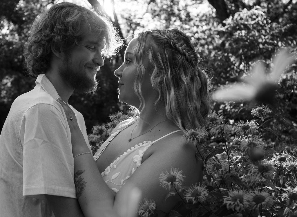 Black and white portrait capturing a joyful moment in a flowering garden.