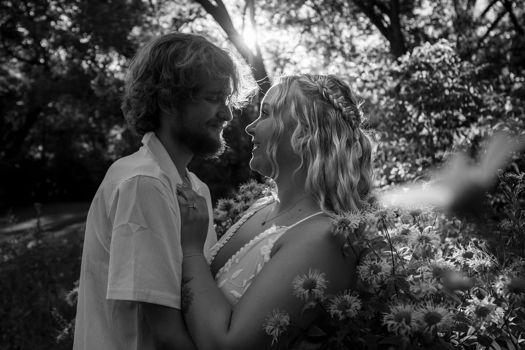 Romantic couple embraces in a sunlit garden setting during golden hour.