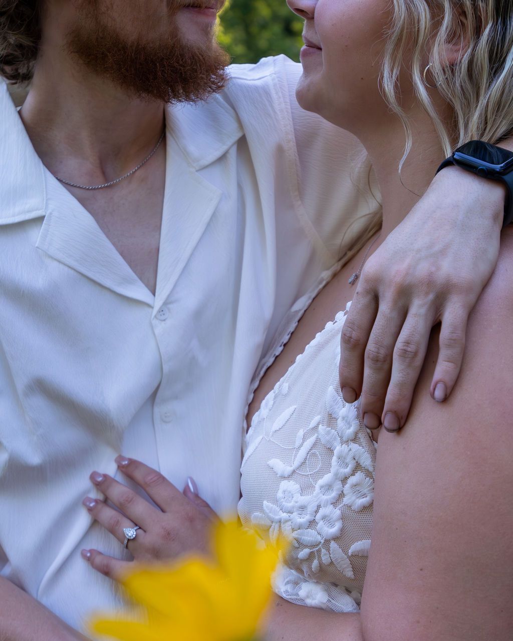 Close-up shot of couple embracing in white summer attire.