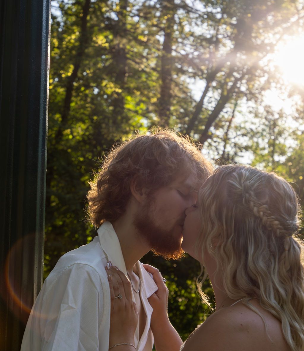 Golden sunlight filters through trees as couple shares tender moment.