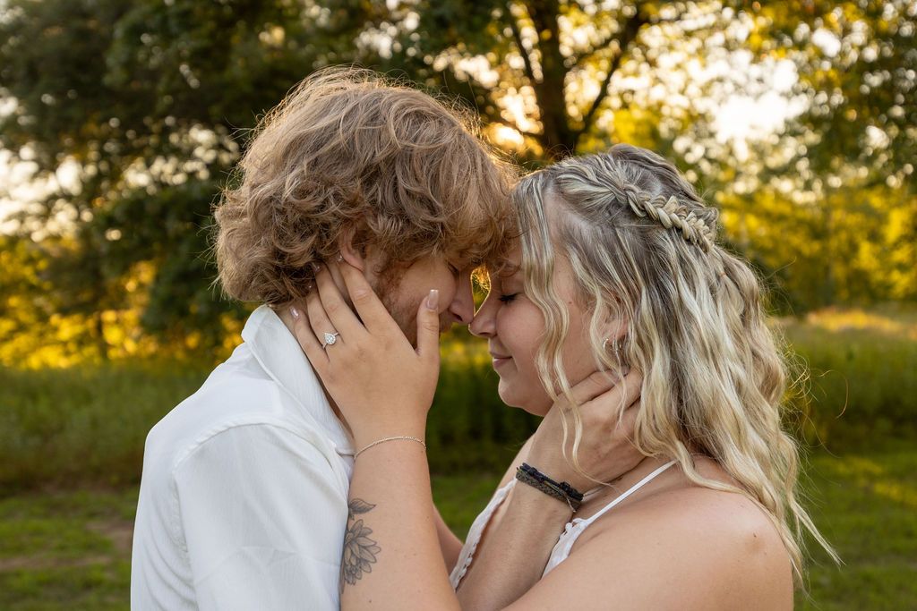 Romantic couple embracing in a sun-dappled outdoor setting.