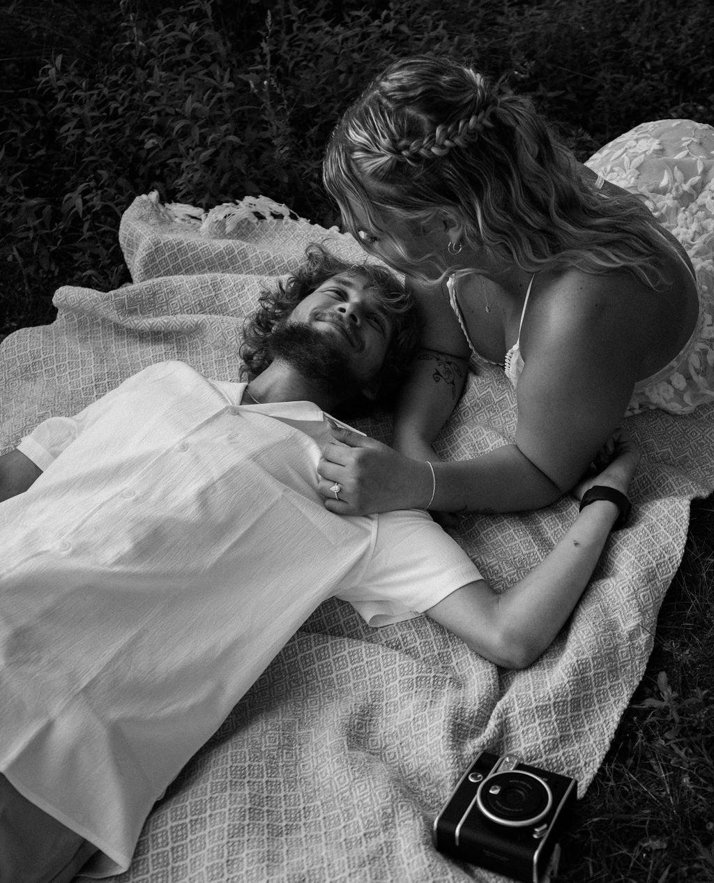 Artistic black and white photo of a couple resting on a textured blanket.