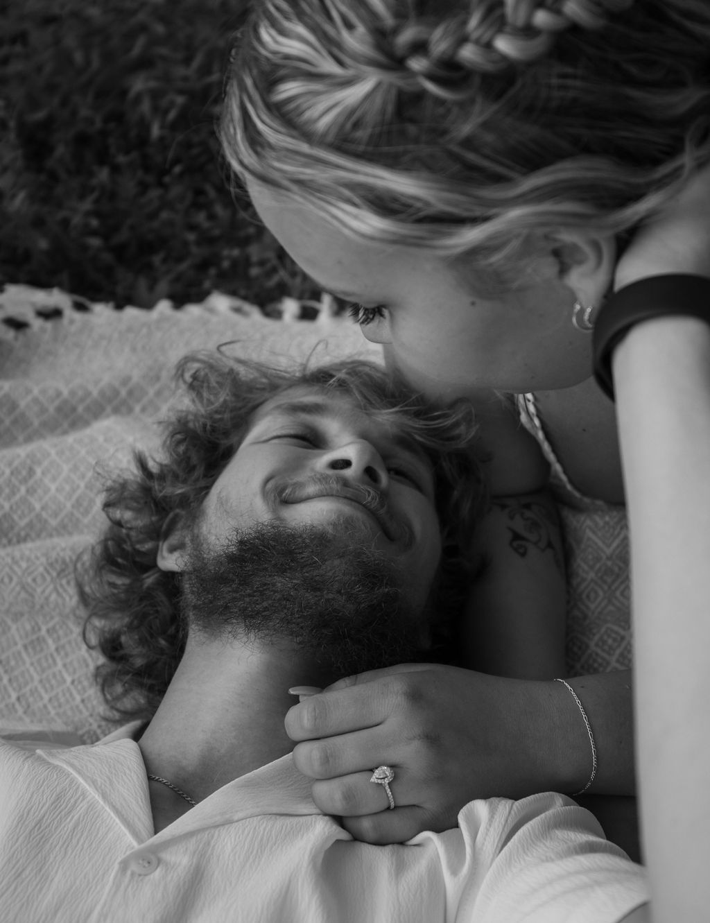 Black and white portrait of a couple sharing a tender moment while laying on a blanket.