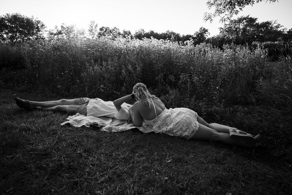 A couple relaxes together on a blanket in a wildflower field at dusk.