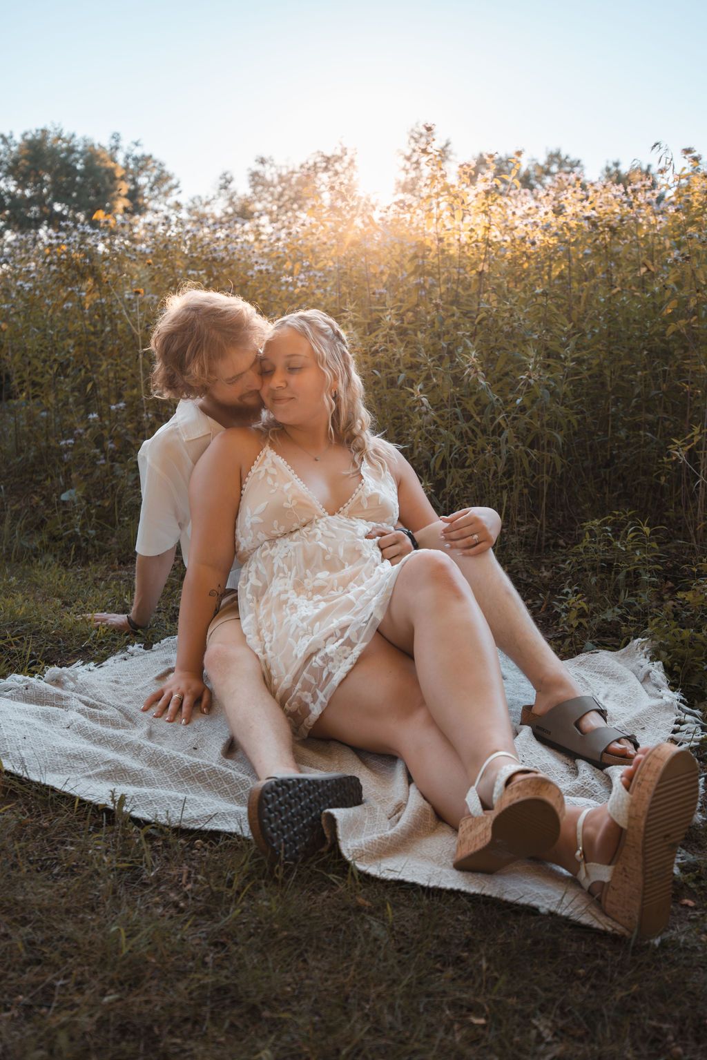 Romantic sunset portrait of couple sharing intimate moment on picnic blanket.