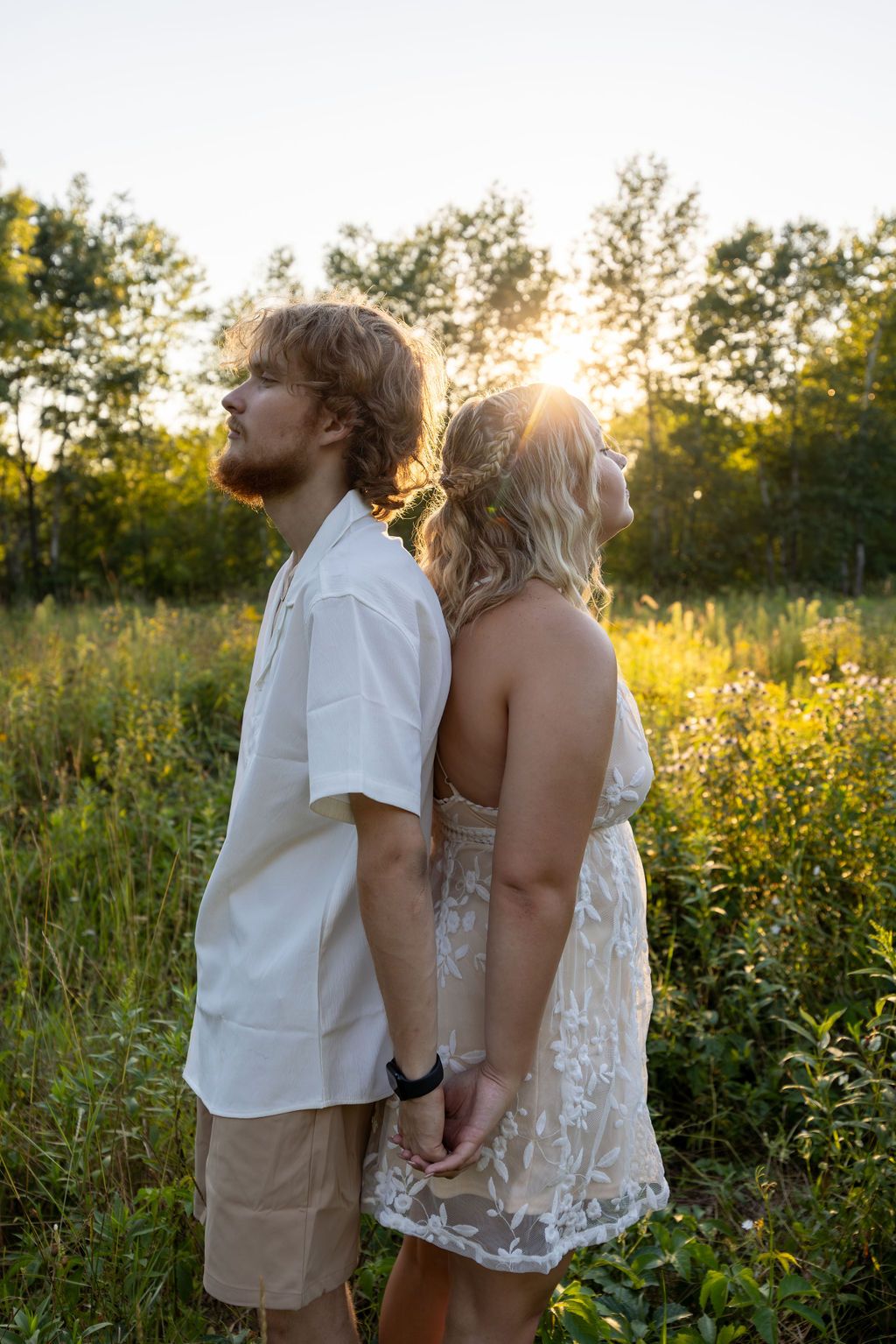 Romantic couple embraces in a sunlit wildflower meadow at golden hour.