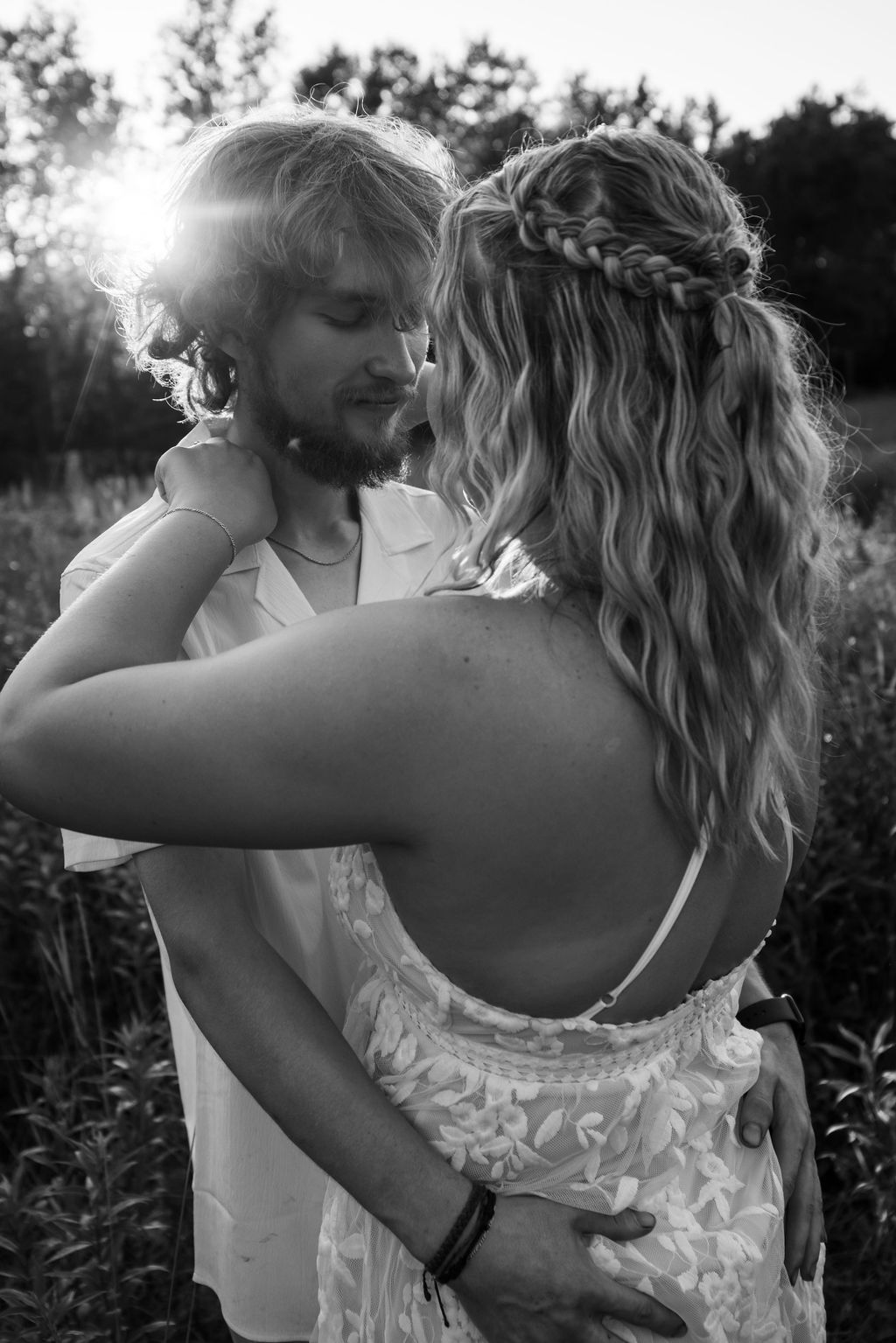 Intimate couple moment captured in natural outdoor setting with lace dress details.