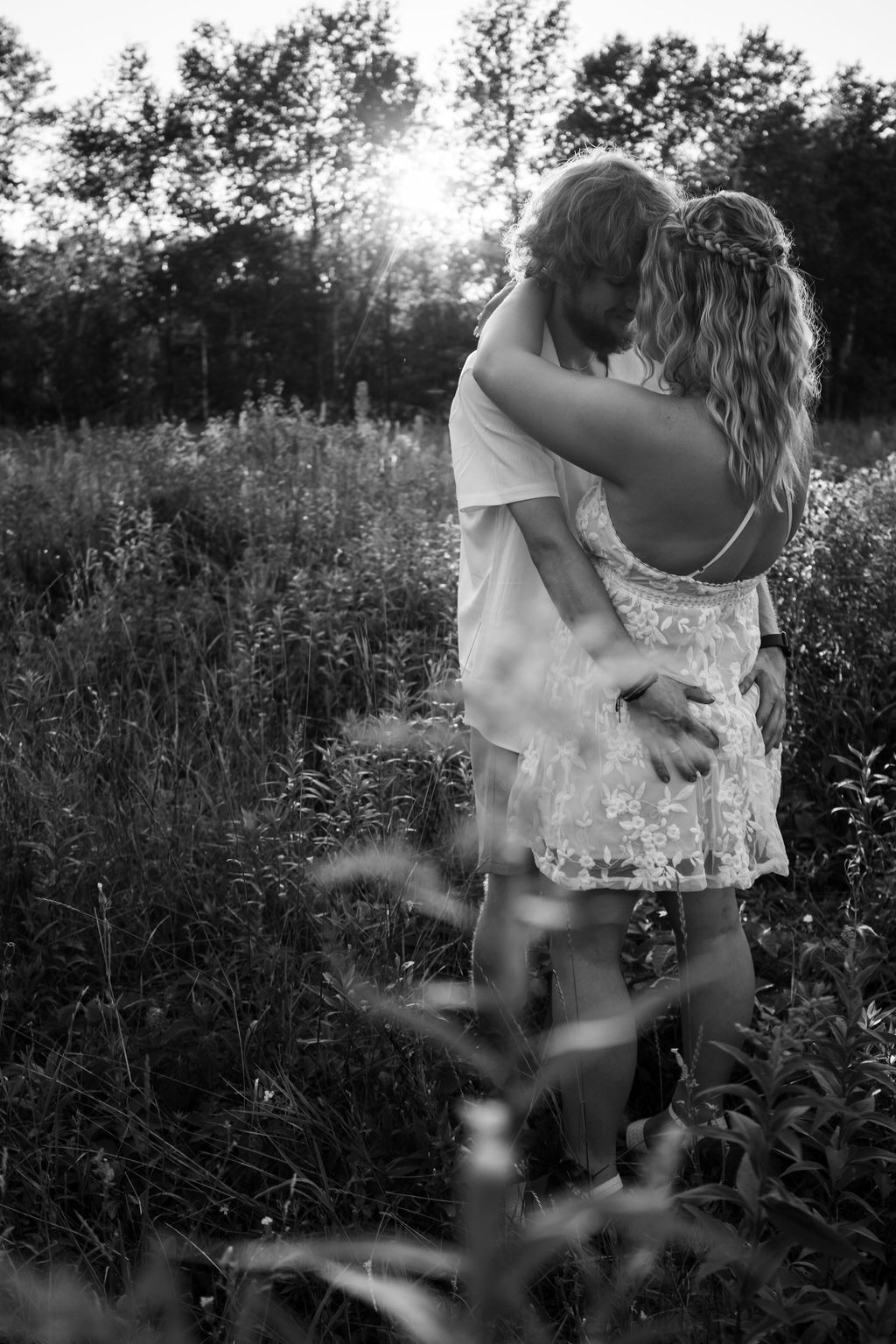 Artistic black and white shot of couple's tender embrace in wild meadow.