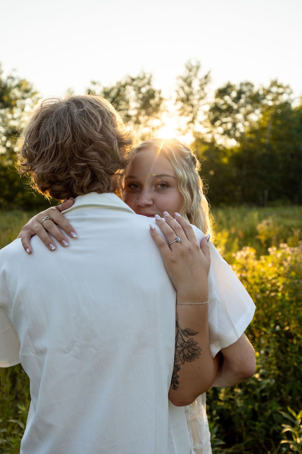 Romantic sunset portrait showing couple's intimate embrace in wildflower field.