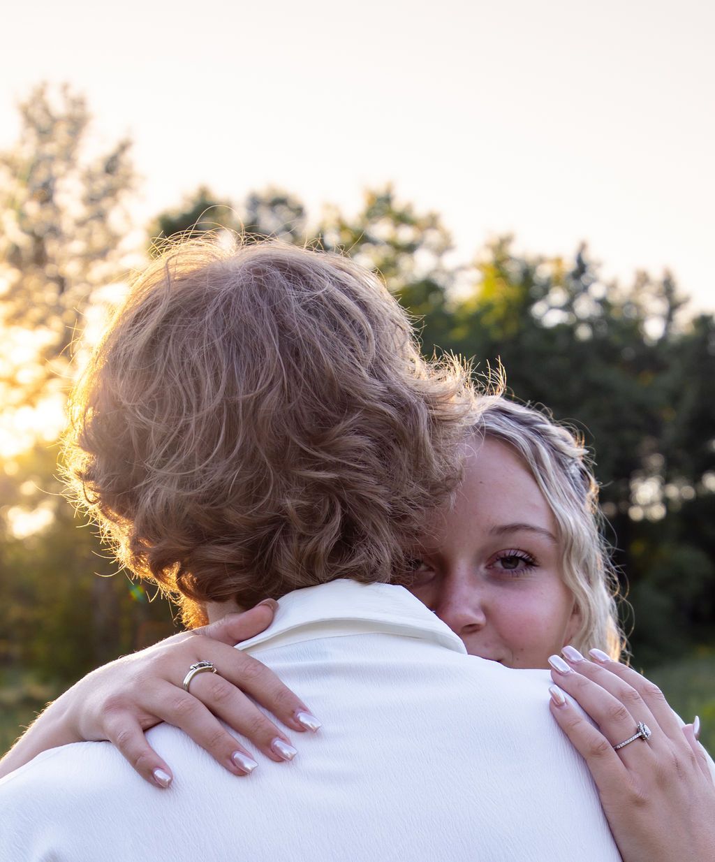 Soft focus portrait of couple's tender moment with golden sunlight behind.