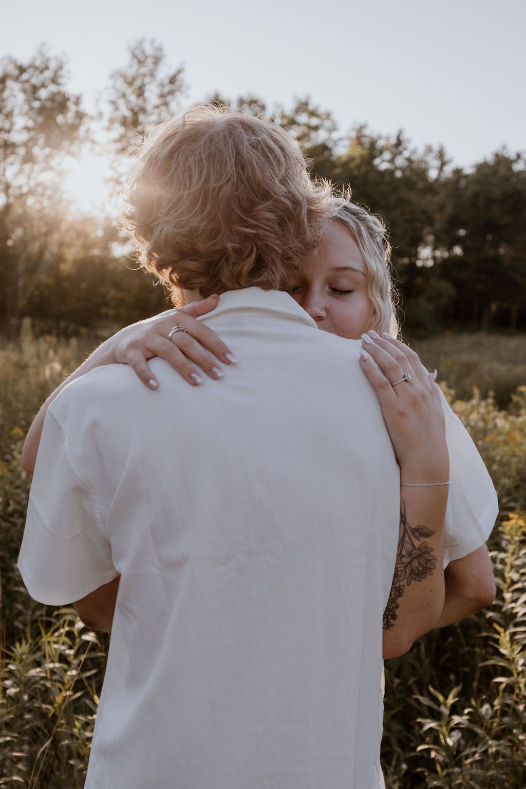 An intimate outdoor portrait showing an emotional embrace at golden hour in a summer field.