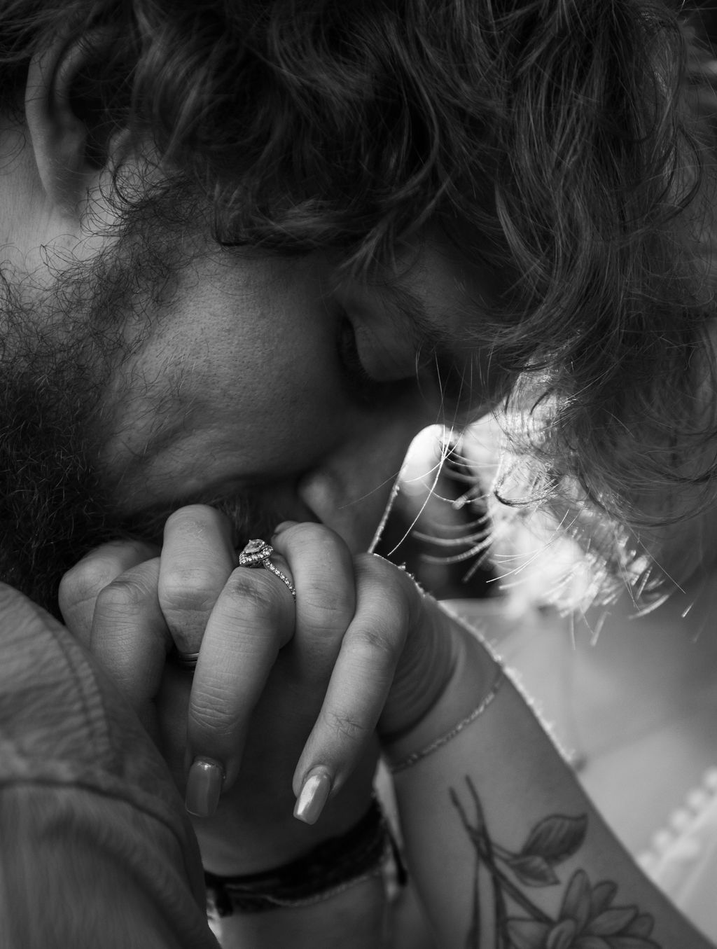 Close up black and white intimate shot showing a gentle kiss on hand during romantic moment.