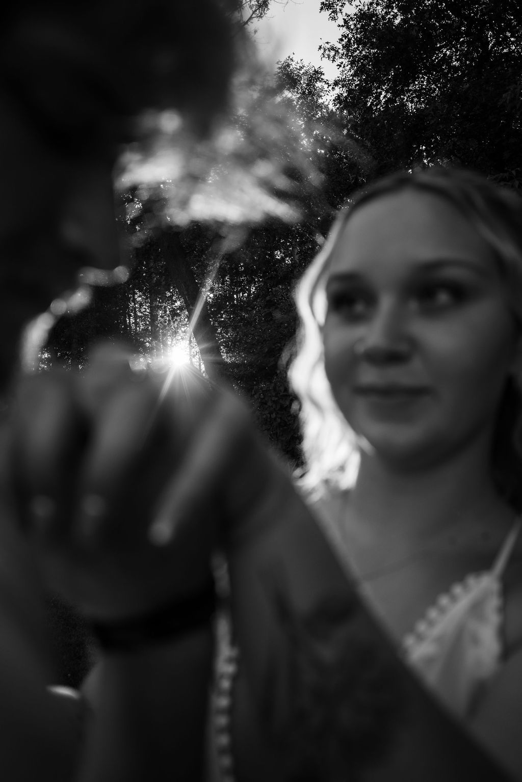Artistic black and white photo with sunburst through trees creating dreamy atmosphere.