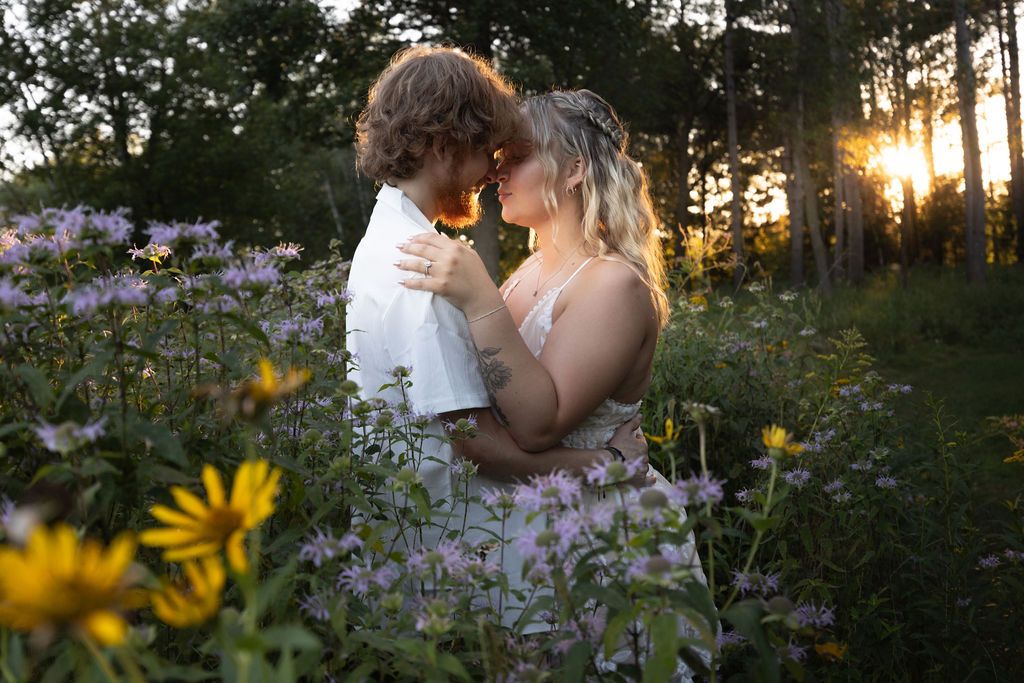 Tender embrace captured in wildflower meadow with golden sunset light.