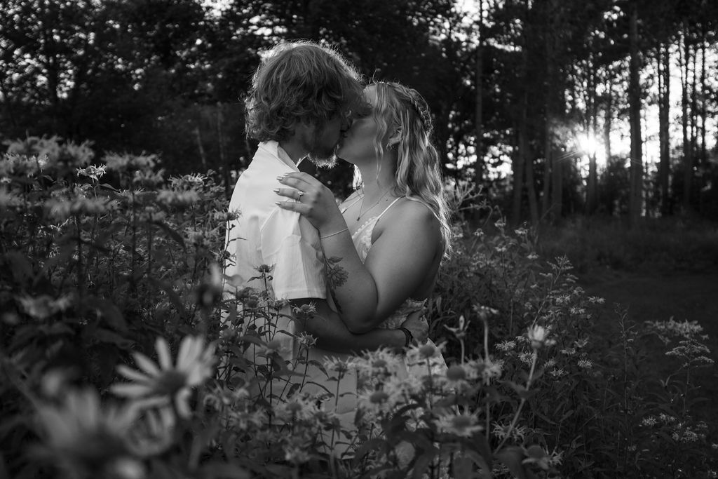 Black and white portrait of couple's intimate moment among wild daisies.