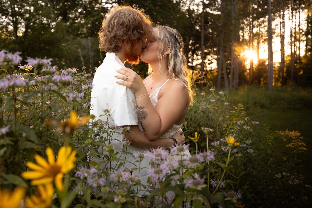 Intimate moment between couple surrounded by purple and yellow wildflowers at dusk.