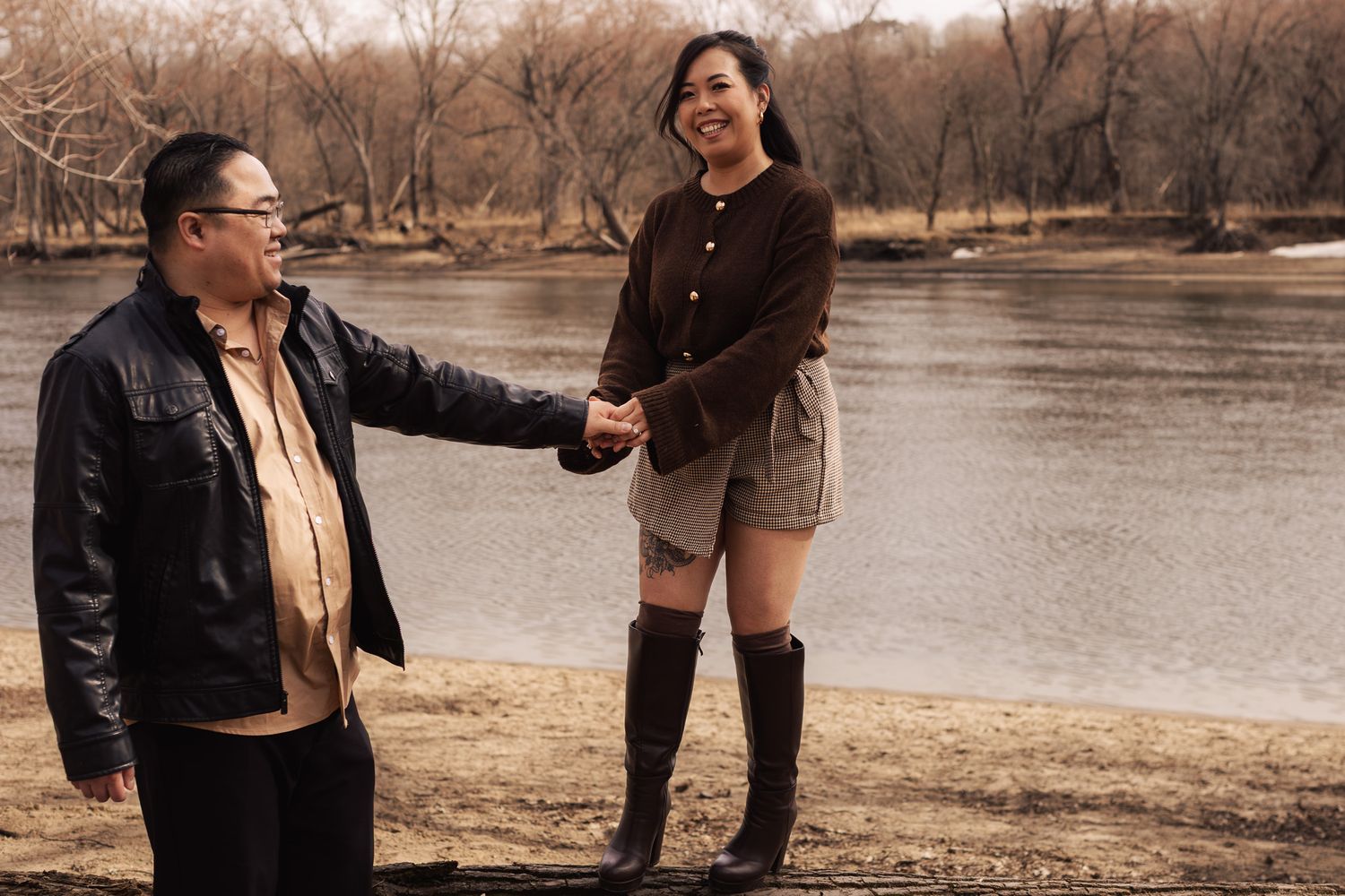 A couple shares a tender moment by the water's edge in a scenic park during golden hour.