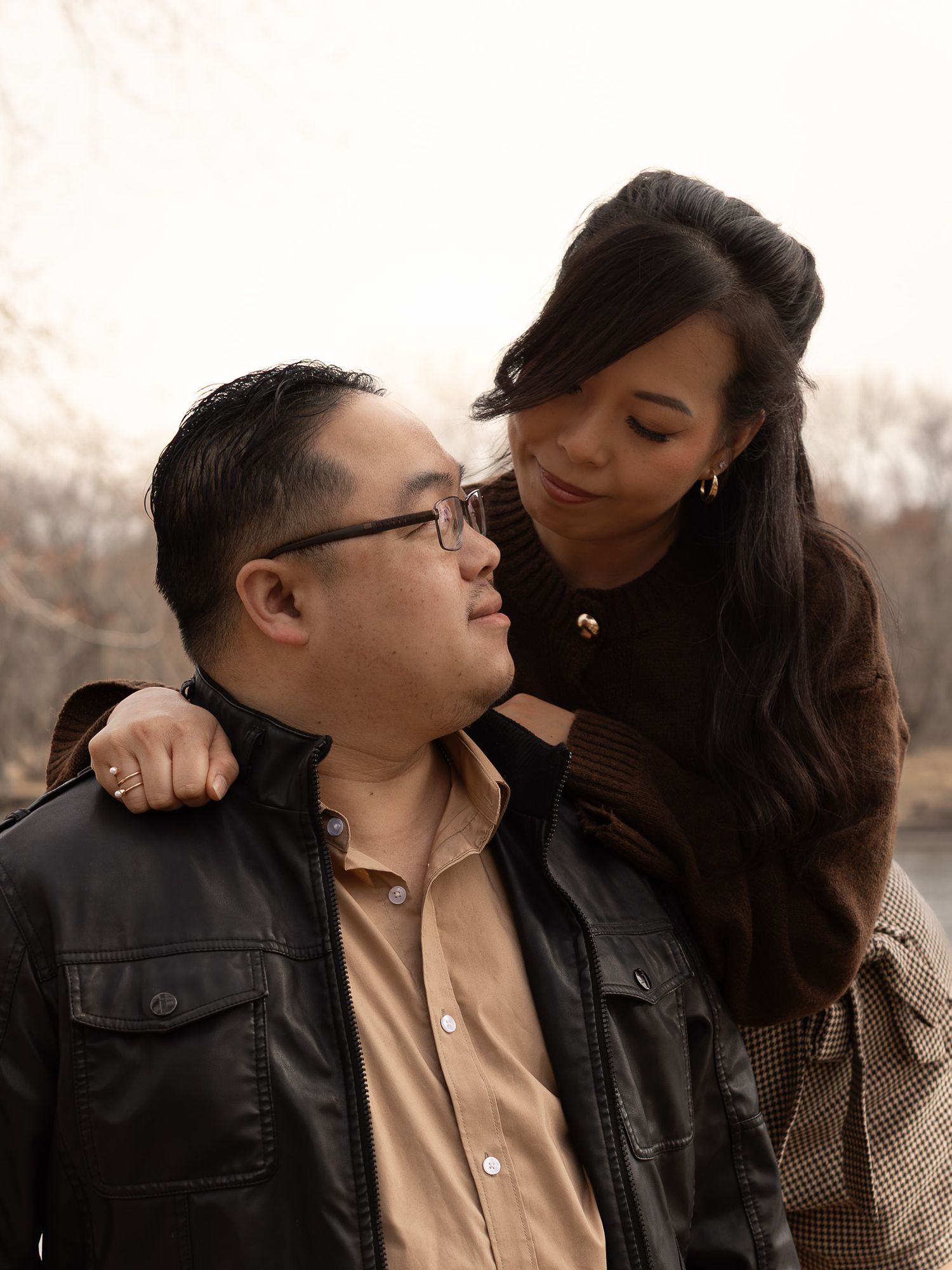 A romantic couple shares an intimate moment while wearing casual attire against a soft, warm background.