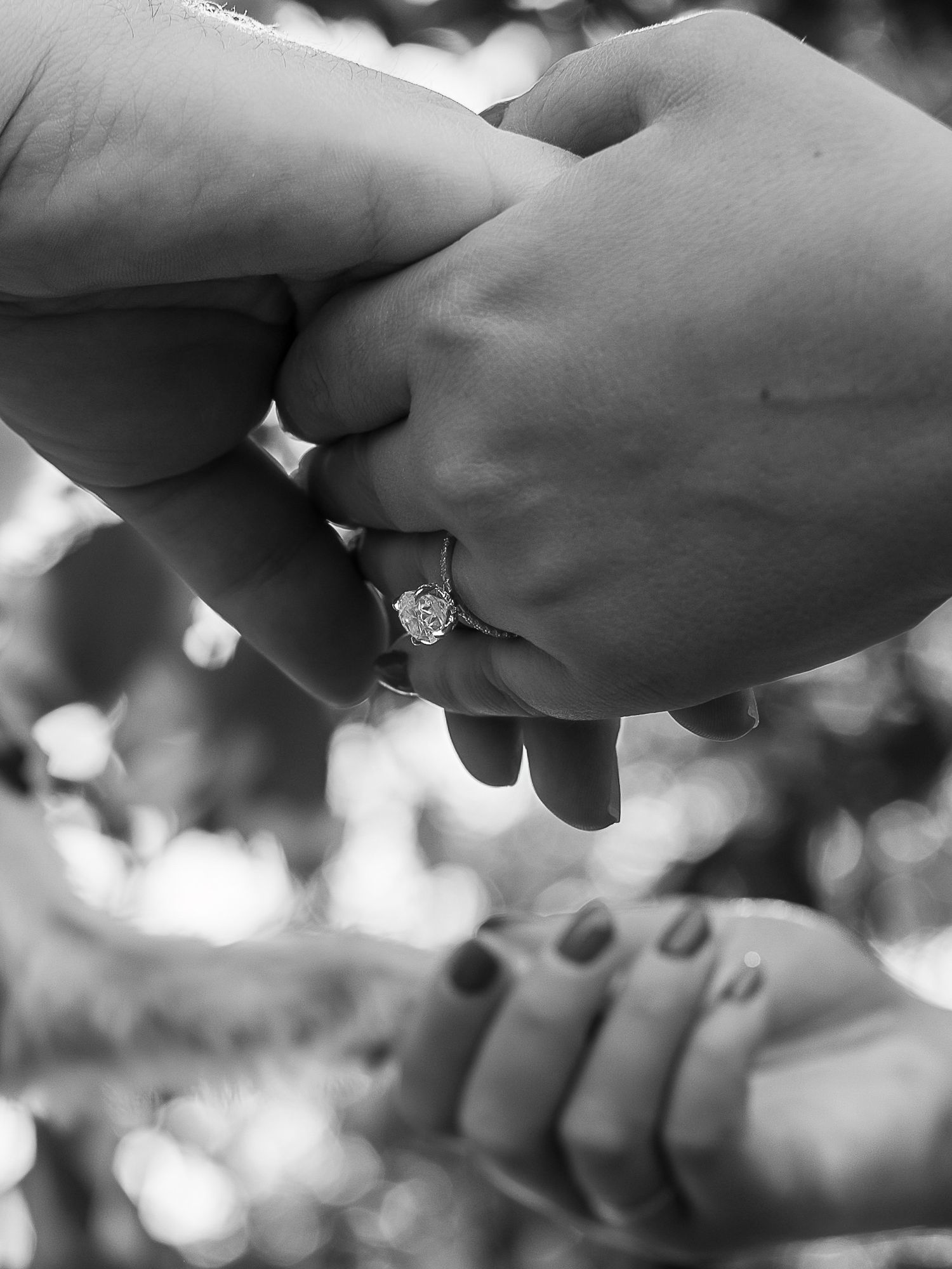A series of black and white close-up shots showing hands wearing engagement rings and wedding bands in tender moments.