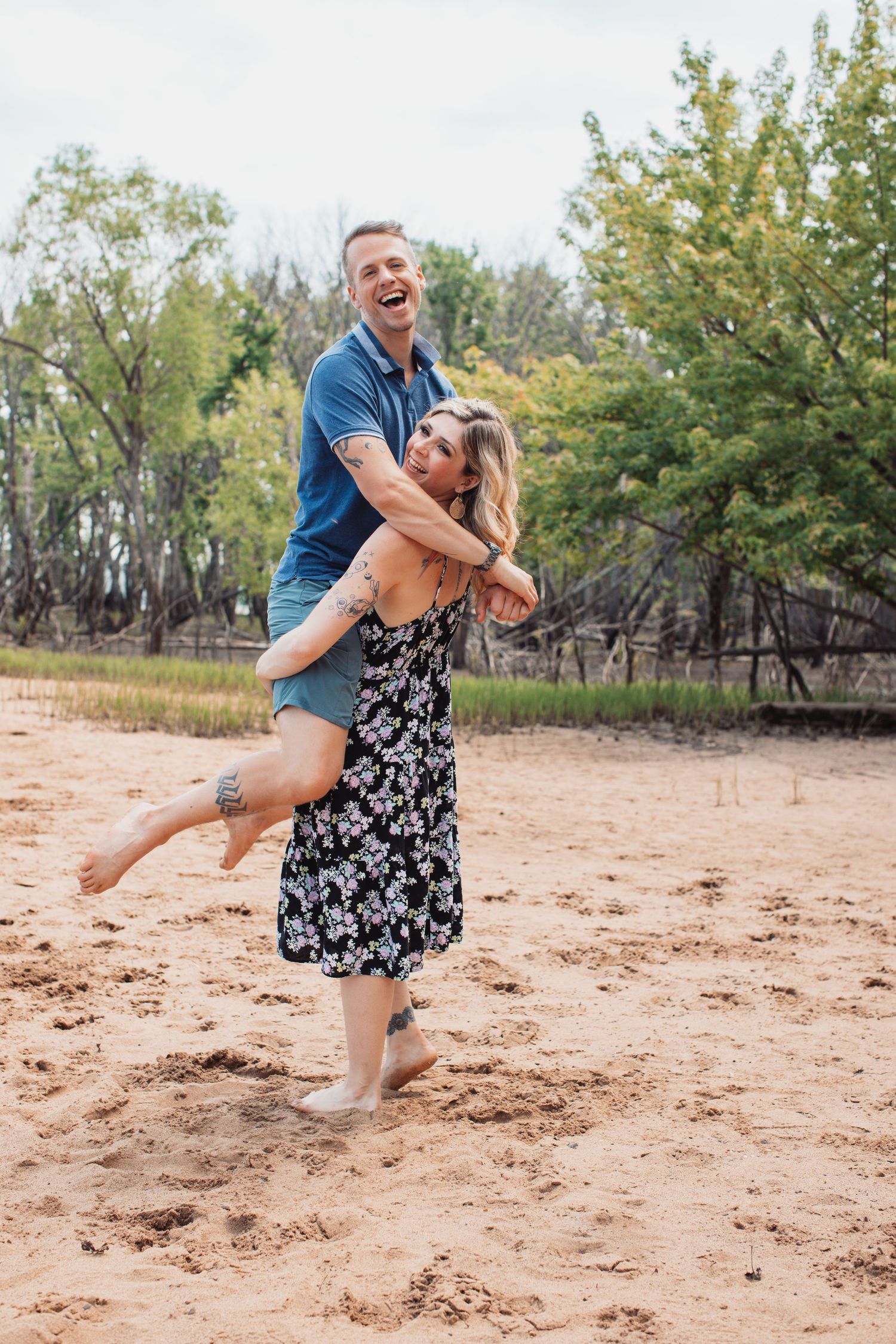 Joyful couple playing and laughing together on a sandy beach.