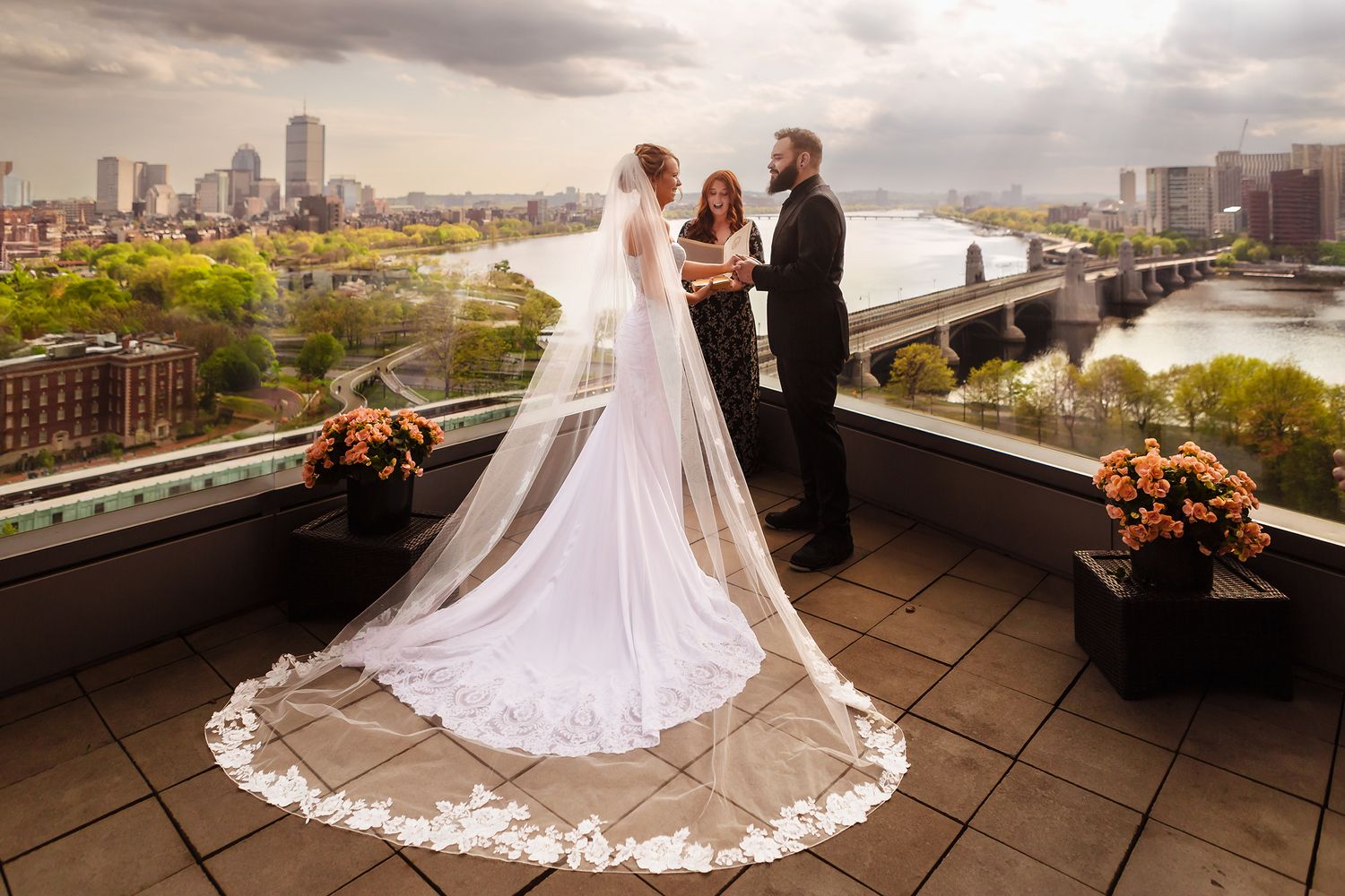 Intimate wedding ceremony on a balcony at The Liberty Hotel overlooking the Charles River and downtown Boston skyline with bride and groom