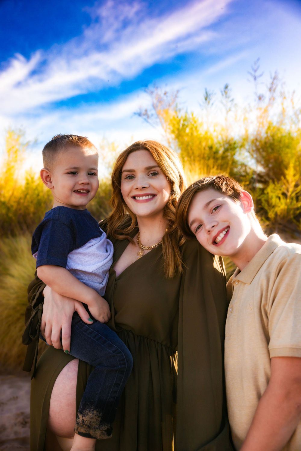 A group poses together outdoors at sunset with golden light and blue sky in the background.