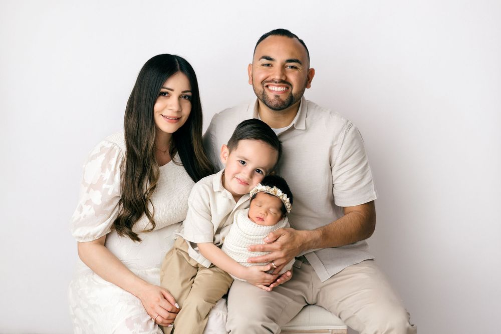 A family in white outfits poses together on a white backdrop in three similar photos showing different poses.