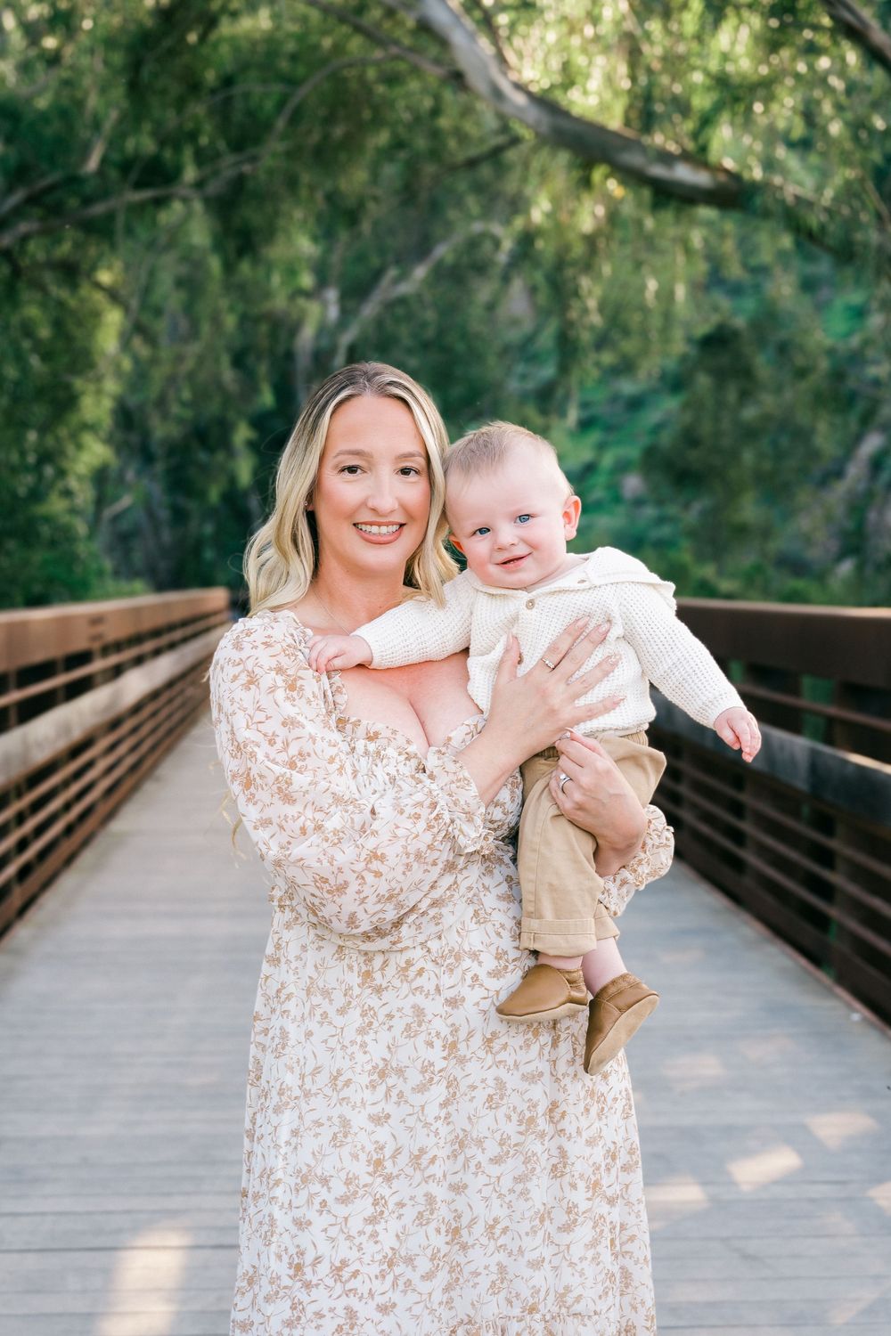 A series of photos on a wooden bridge walkway shows tender moments between parent and child in matching cream outfits.
