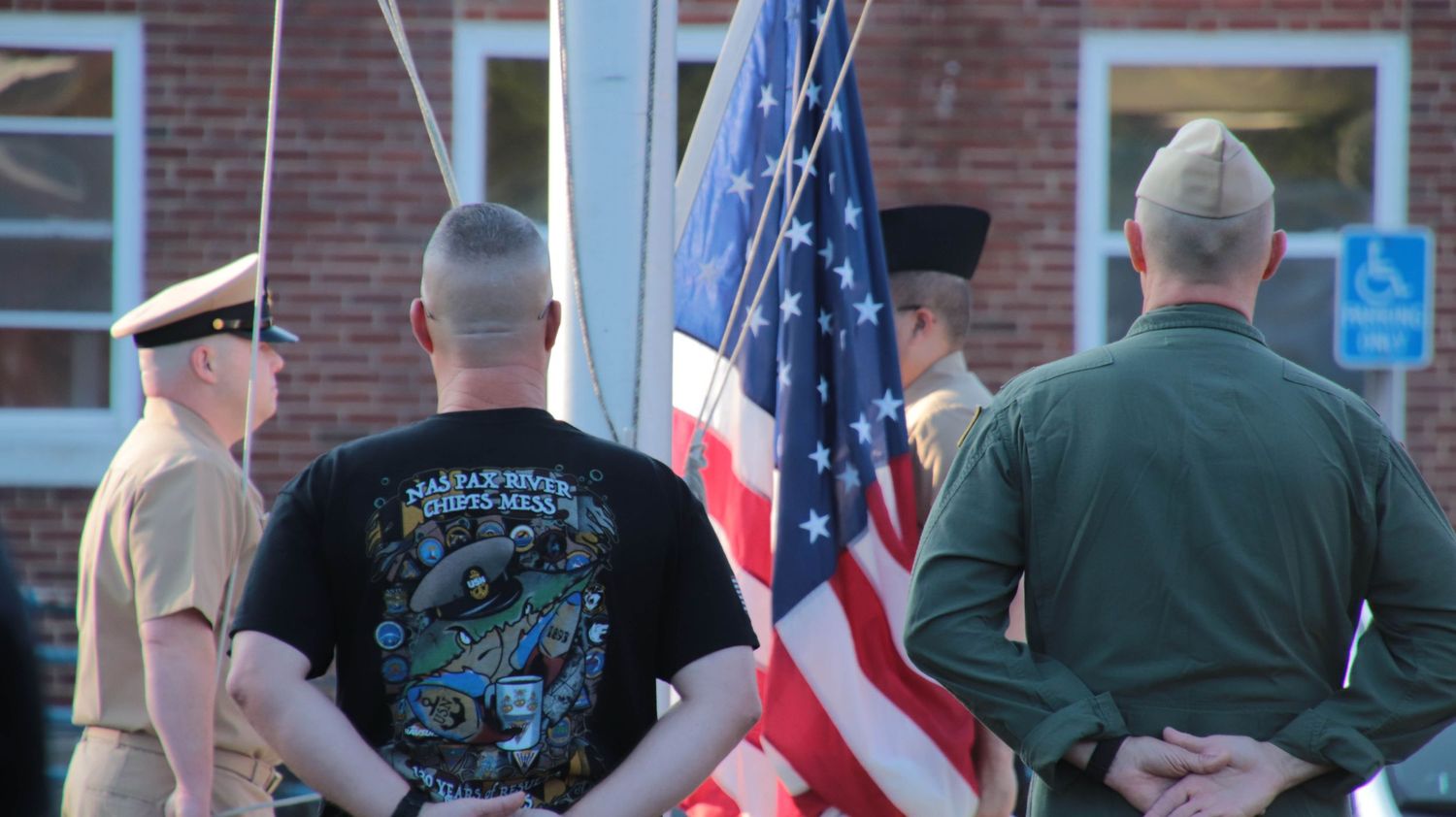 Military photography of U.S. Navy personnel observing morning colors, highlighting the camaraderie of the Chiefs Mess at a Naval Air Station