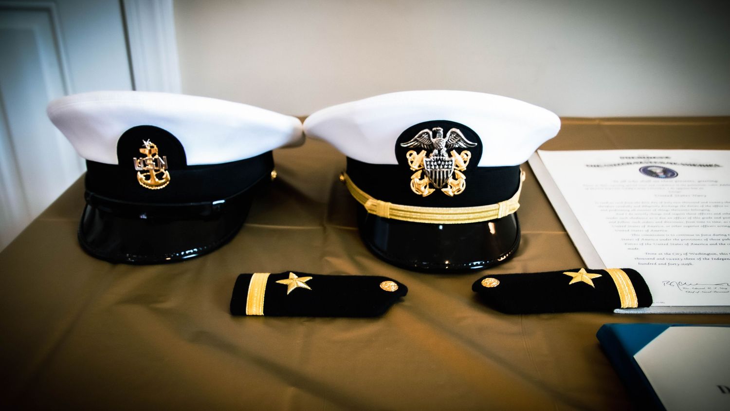 A visual representation of a 'Mustang' ceremony: A Senior Chief combination cover (E-8) resting next to a pristine Officer cover