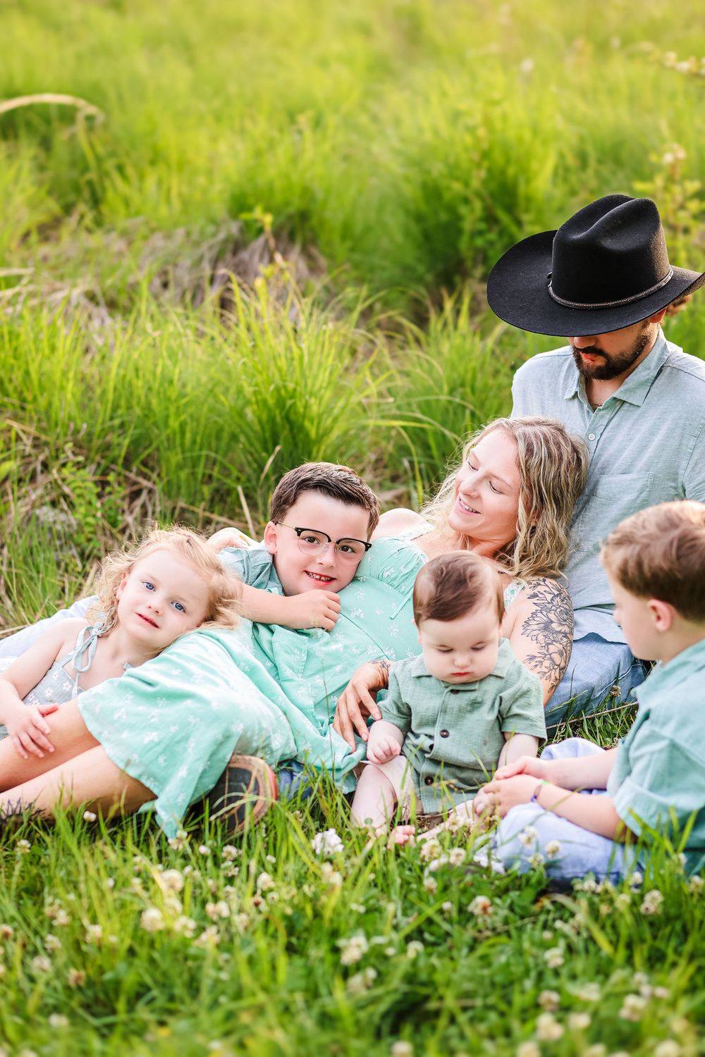 A candid lifestyle image of a family snuggling together laying in the grass.
