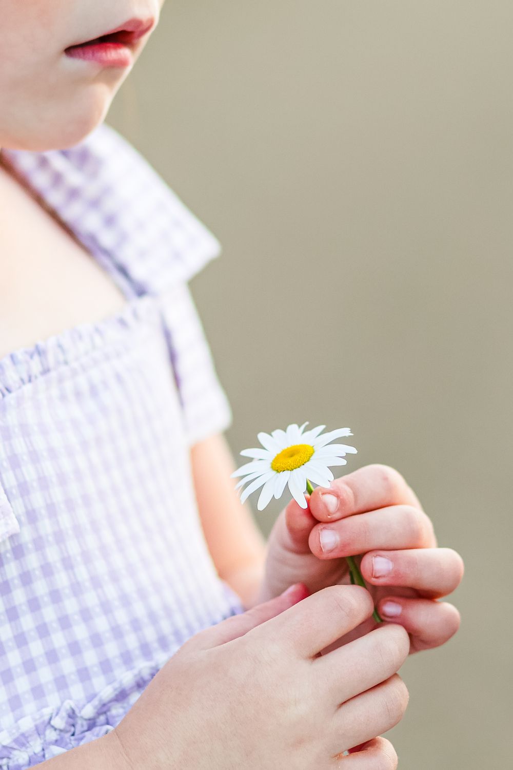 A close-up image of a young girl holding a white flower.