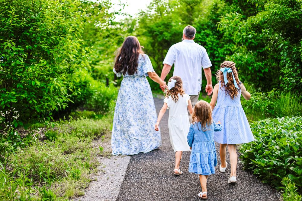 A lifestyle image of a family holding hands and walking away through greenery.