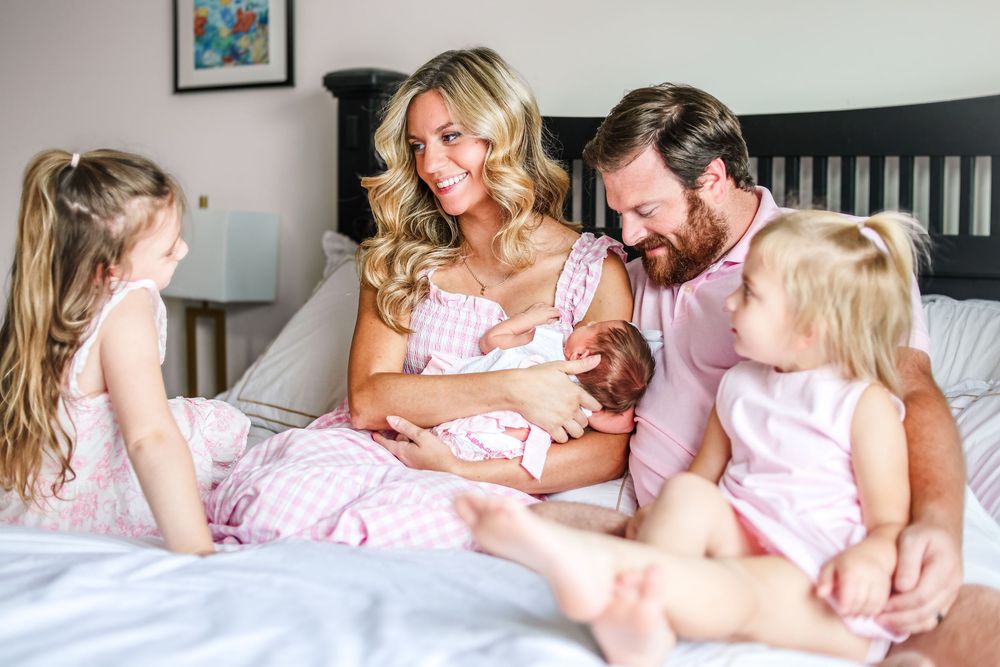 A lifestyle picture of a family sitting in a bed during an in-home newborn photoshoot