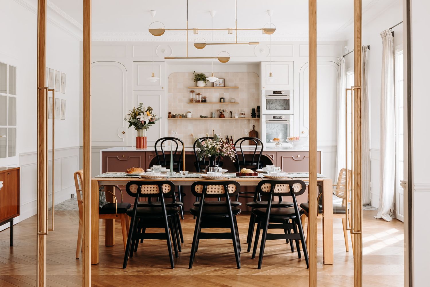 Elegant dining room with hanging pendant lights, framed artwork and velvet accent pillows.