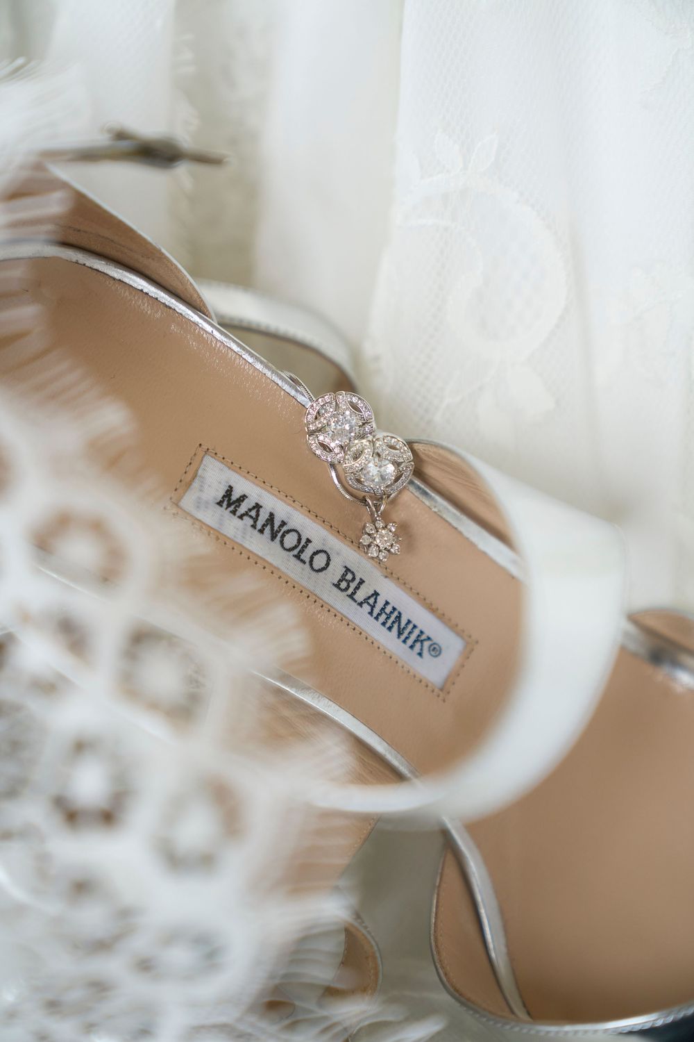 Close-up views of a Manolo Blahnik wedding shoe and diamond engagement ring against a white background.