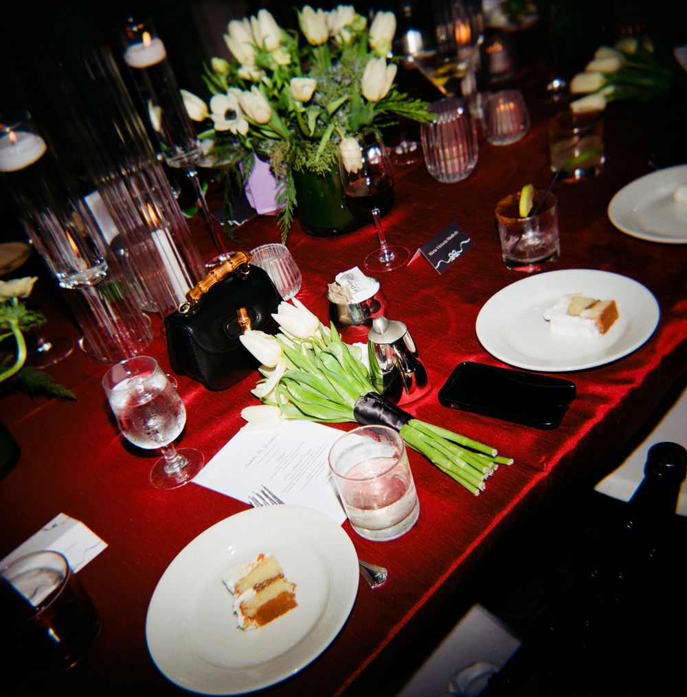 An elegant dinner table setting with white tulips and glassware on a deep red tablecloth.