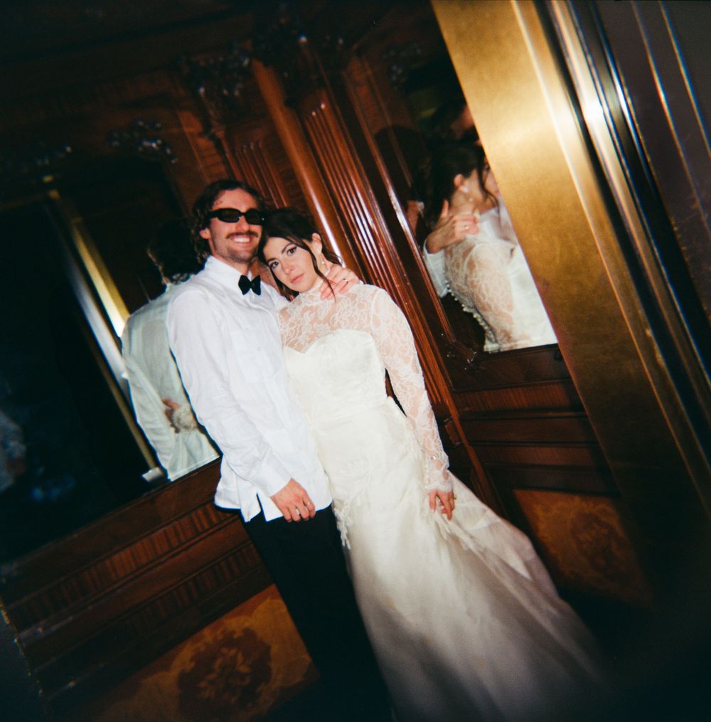 A couple dancing together at their wedding reception in a dimly lit venue with warm lighting and wooden paneling.