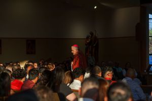 Audience members gather at an indoor event venue listening to a speaker or performance.