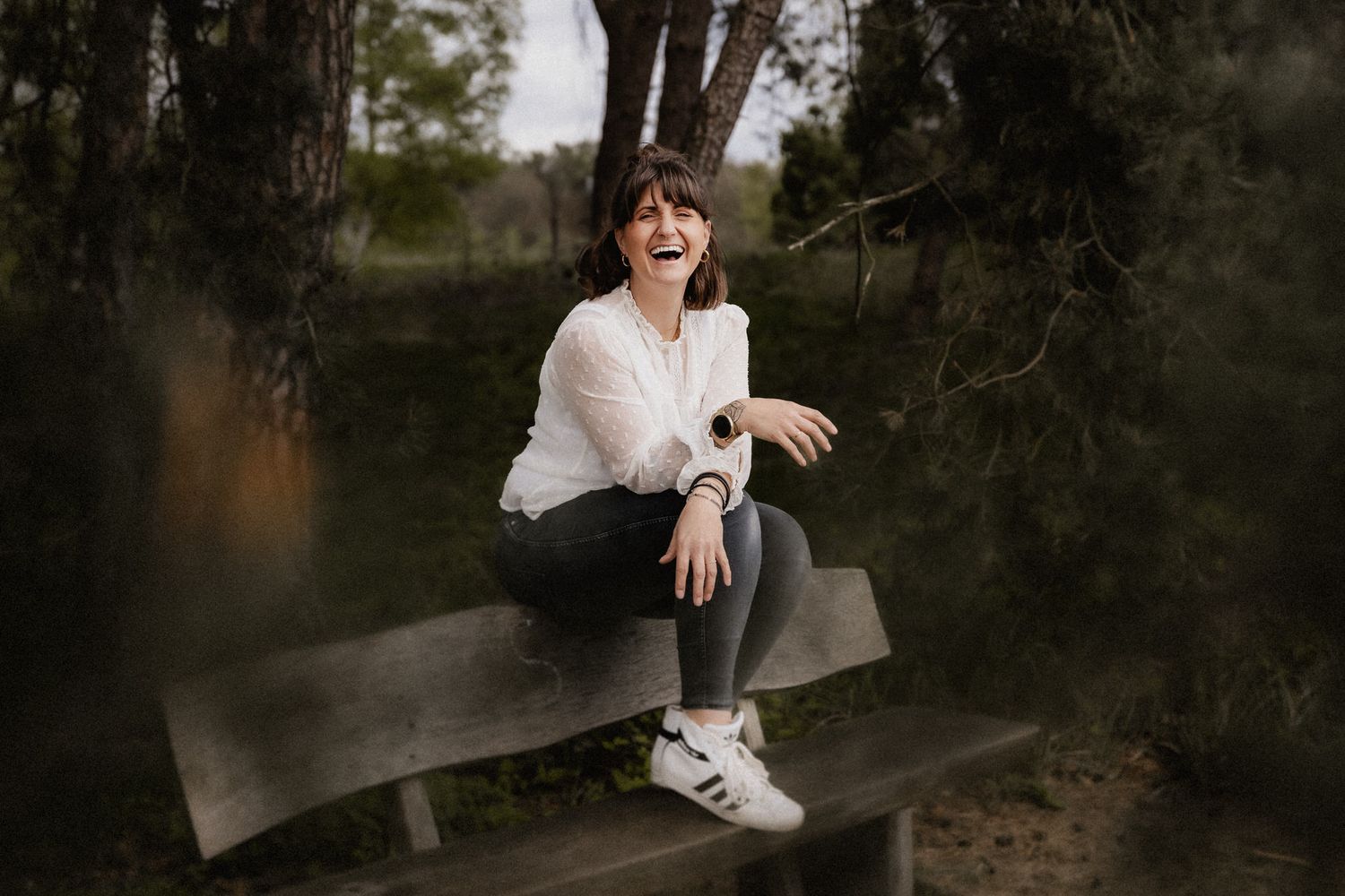 Portrait of someone sitting on a wooden bench in a natural outdoor setting.
