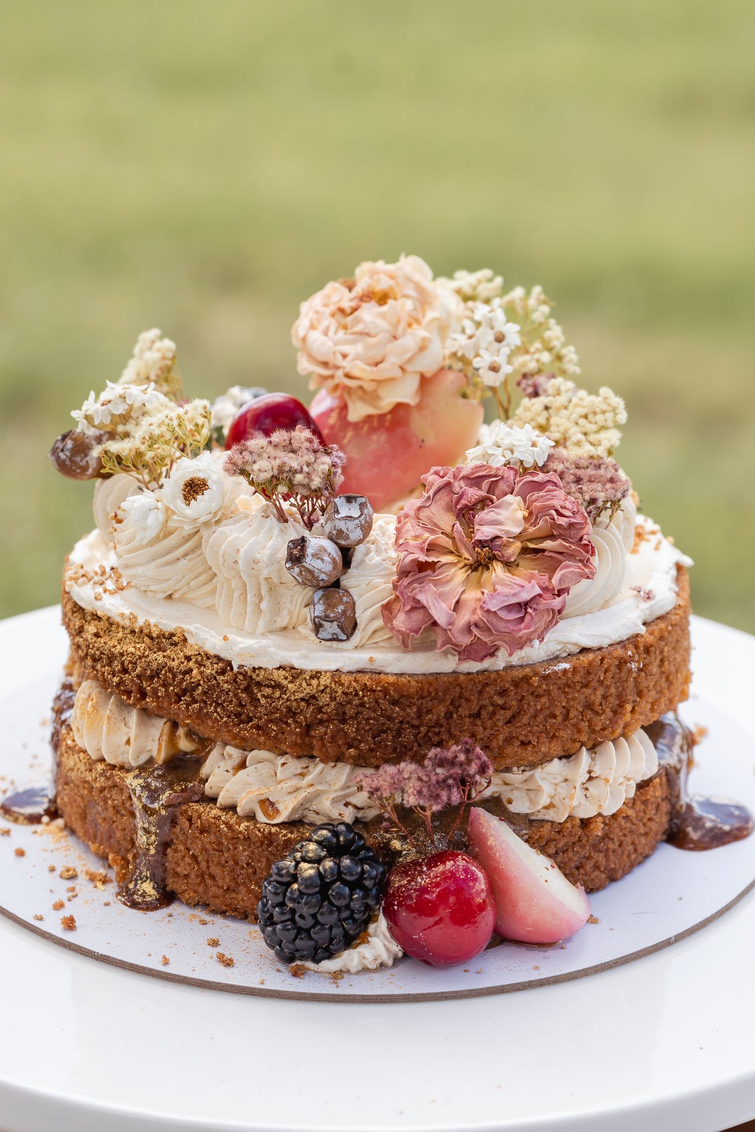 Chocolate cake topped with whipped cream, fresh berries, and edible flowers on a white plate.