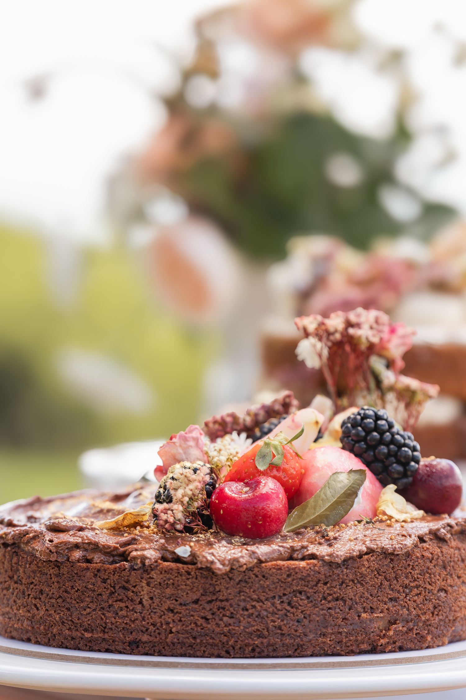 Rustic chocolate dessert decorated with fresh cherries and blackberries on a white serving plate.