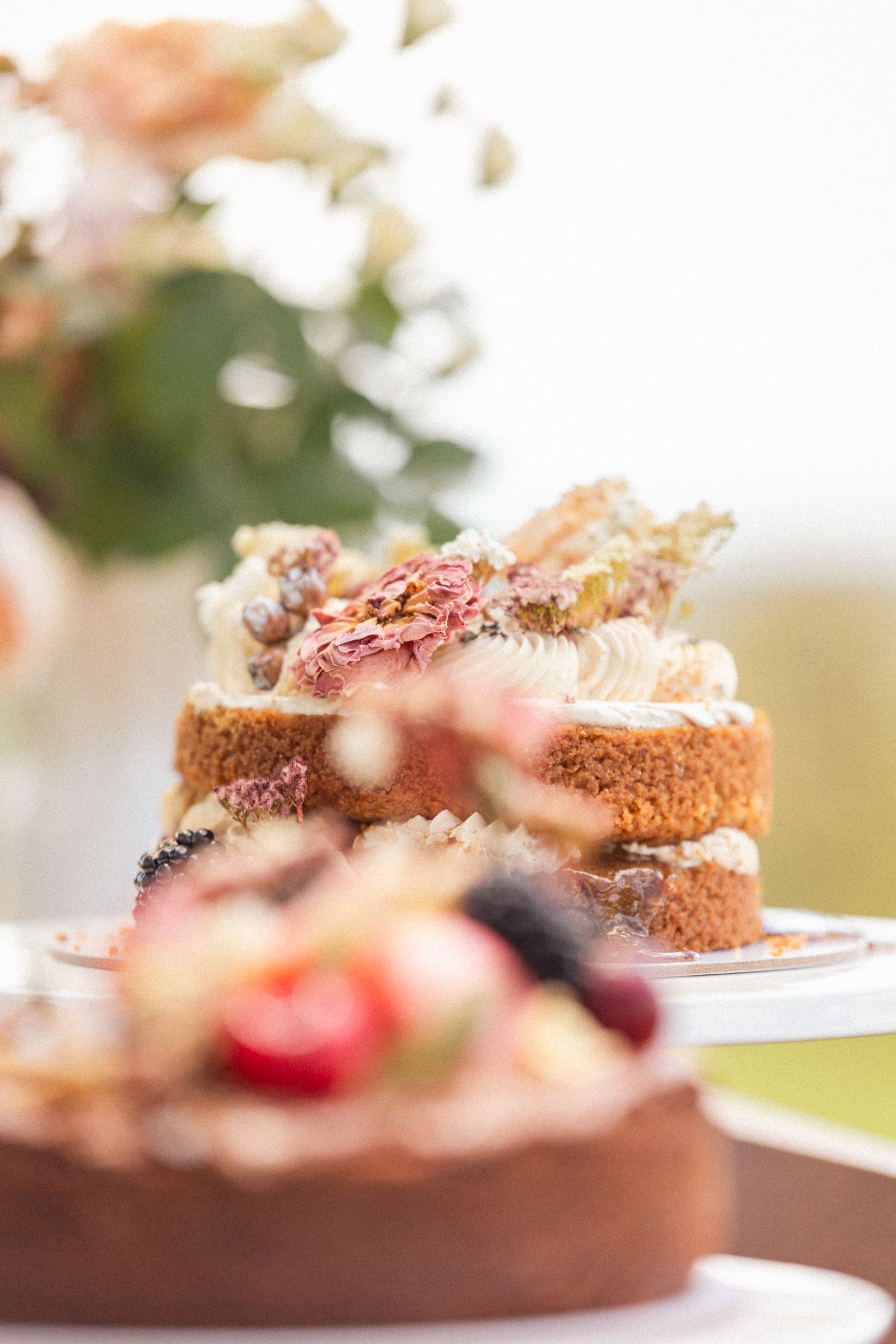 Side view of a chocolate cake garnished with berries and floral decorations.