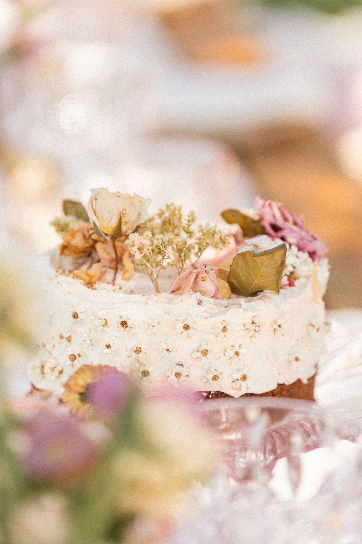 Close-up of delicate cream frosting with floral decorations and gold accents on a dessert.