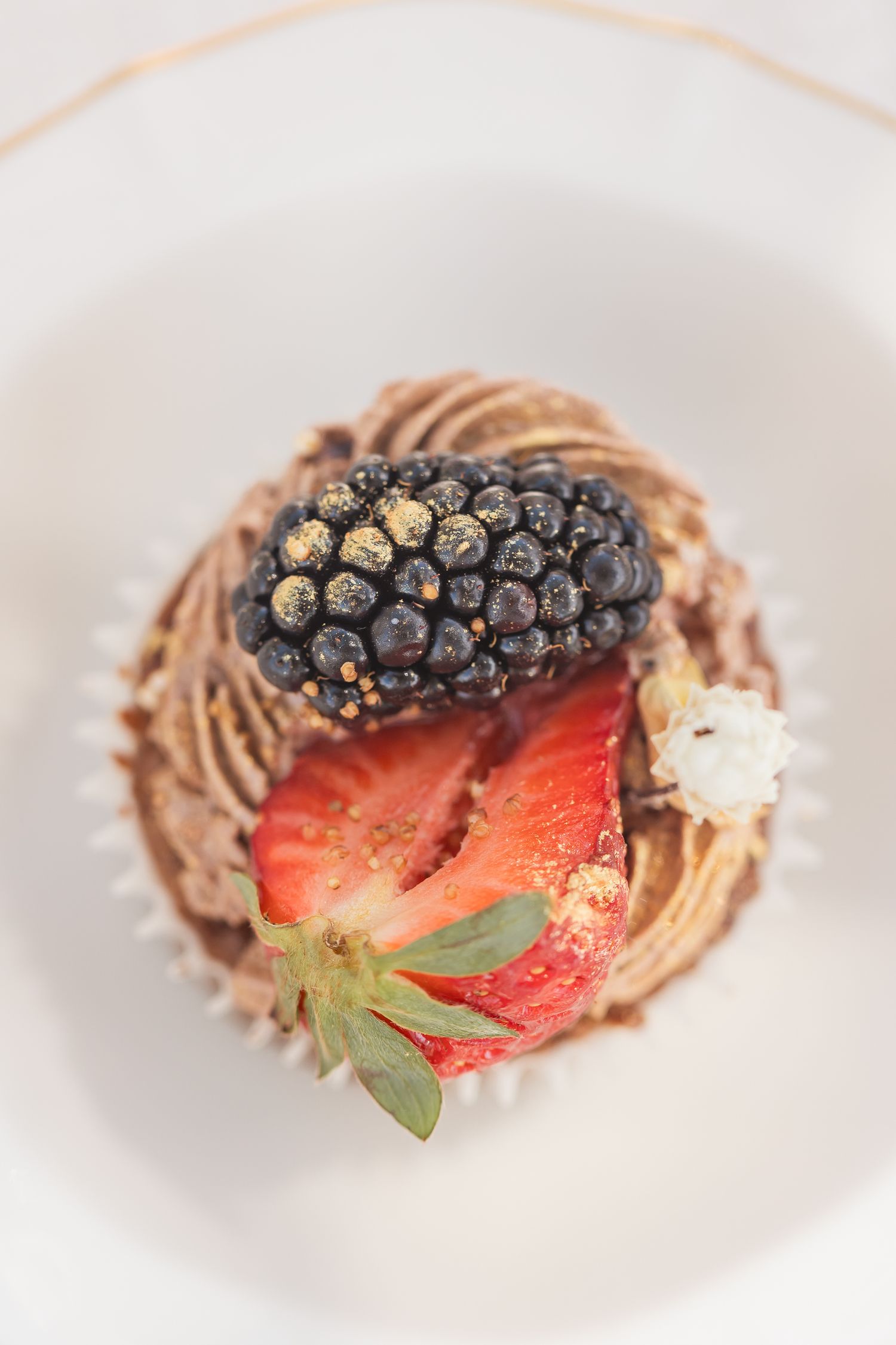 Close-up of chocolate mousse topped with fresh blackberries and strawberries on a white plate.