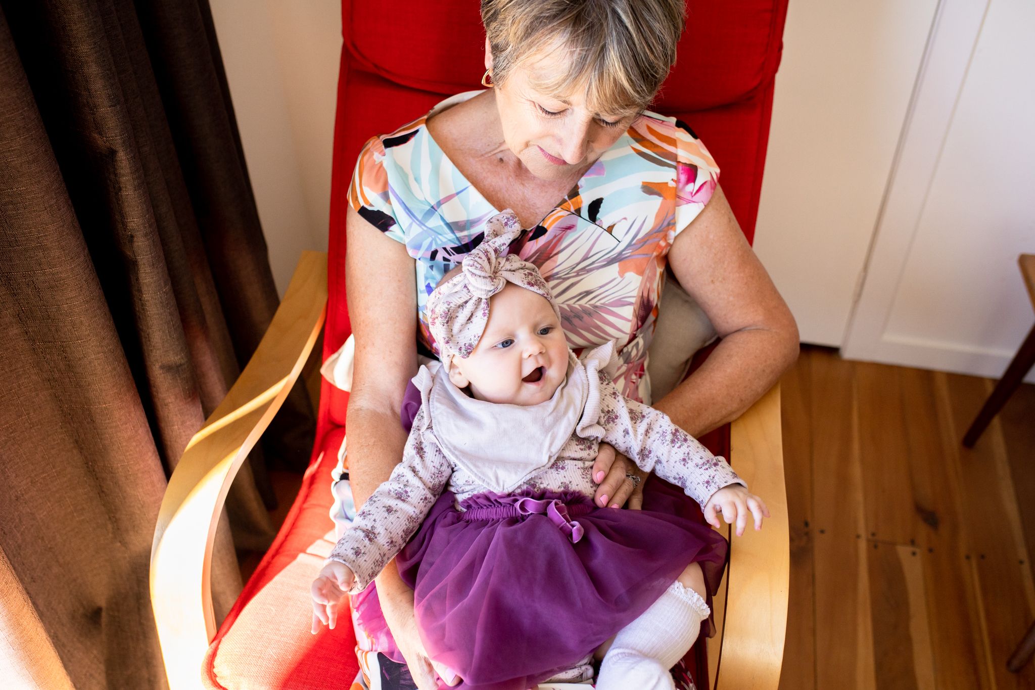 Candid moment of child sitting in red armchair at home.
